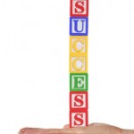 A girl holding colorful wooden blocks that spell success